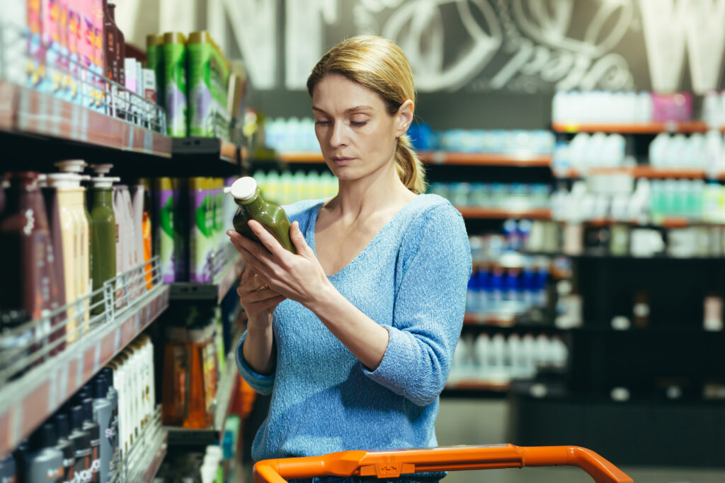 Frau vor Supermarktregal mit Flasche in der Hand