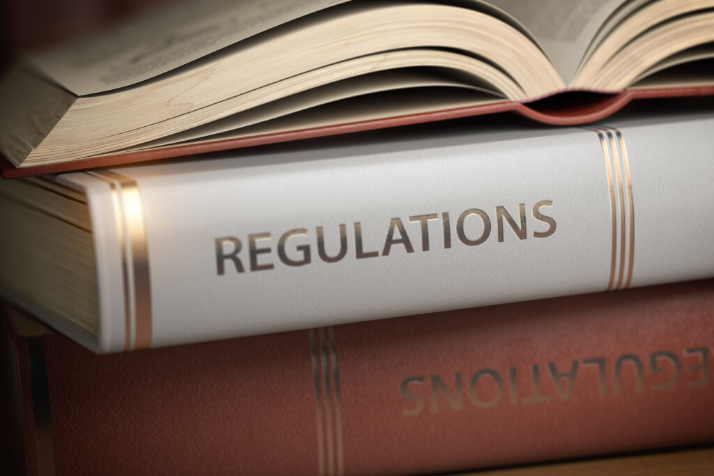 Übereinander gestapelte Bücher, wobei zwei davon mit der Aufschrift "Regulations" gekennzeichnet sind