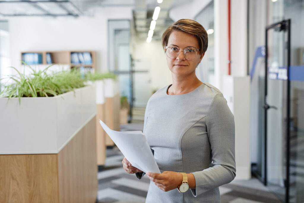 Frau in Business-Outfit hält Unterlagen in der Hand
