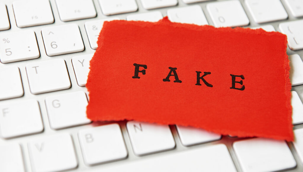 Das Wort Fake auf rotem Papier geschrieben liegt auf einer Computer-Tastatur