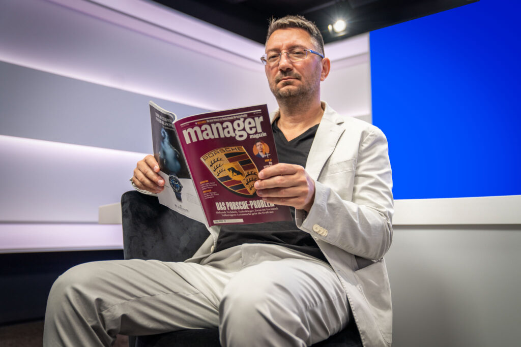 Walter Temmer hält Magazin in den Händen und posiert für die Kamera