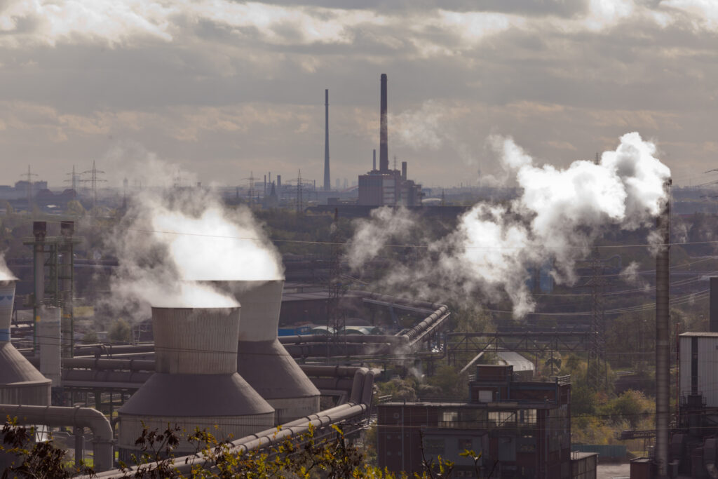 Blick auf eine Industrielandschaft mit rauchenden Kaminen