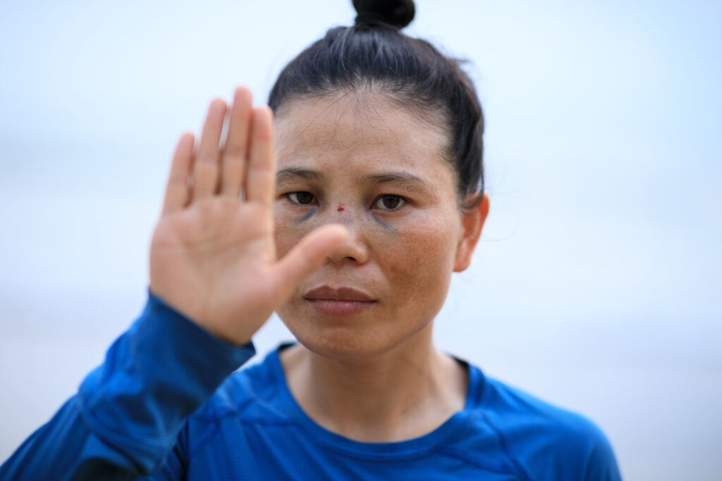 Frau mit asiatischen Wurzeln gibt ein Handzeichen, das als "Stopp" interpretiert werden kann