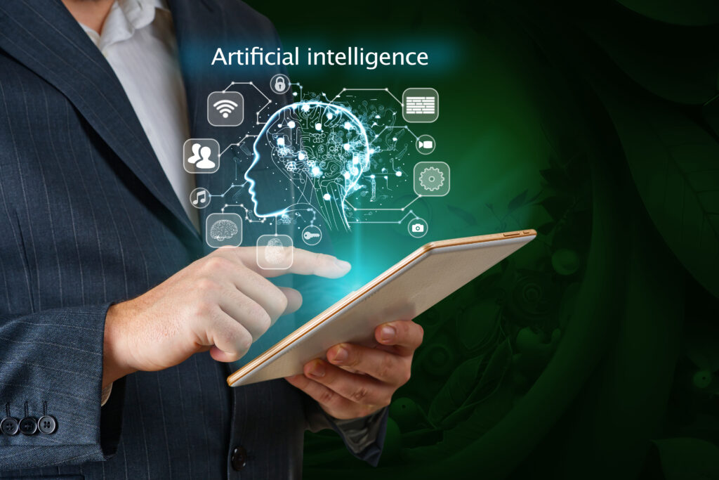 Mann mit einem Sakko hält ein Tablet in der Hand und tippt drauf. Dahinter ein Kopf mit der Überschrift Artificial intelligence und einigen Symbolen