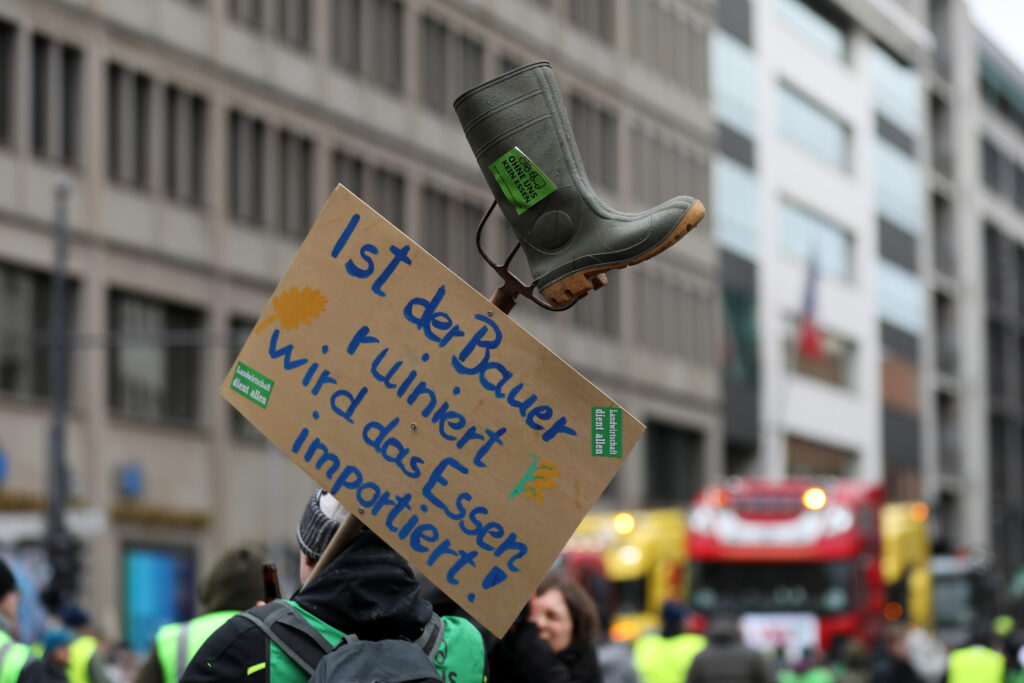 Demonstranten zeigen ein kritisches Plakat im Rahmen der Bauernproteste