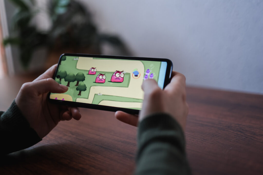Mann hält Smartphone in der Hand und spielt Videospiel