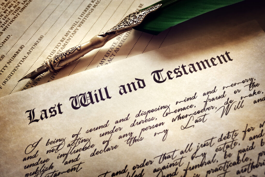 Alte Feder zum schreiben mit spitzem verzierten Stil. Davor ein Papier aus Pergament auf dem Last will and Testament steht