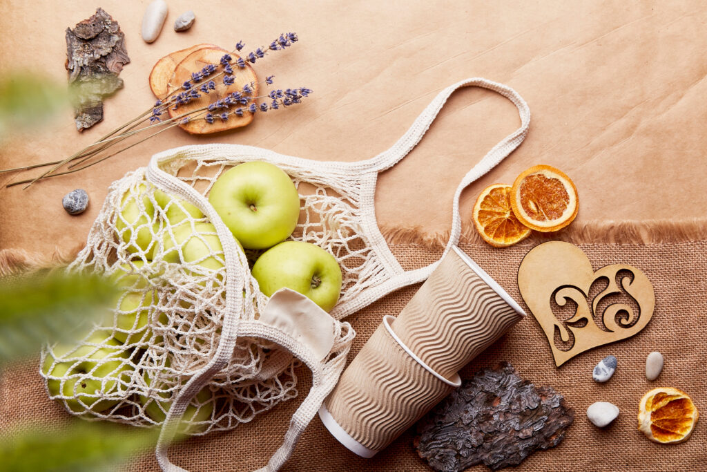 Apfel in einem Einkaufsnetz, daneben Papierbächer, Lavendel und aufgeschnittele, getrocknete Organgenscheiben