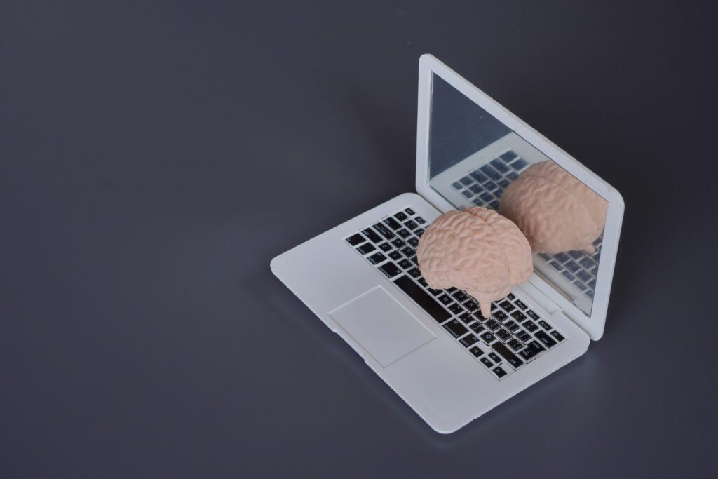 dunkler Hintergrund mit einem Notebook auf dem ein menschliches Gehirn liegt