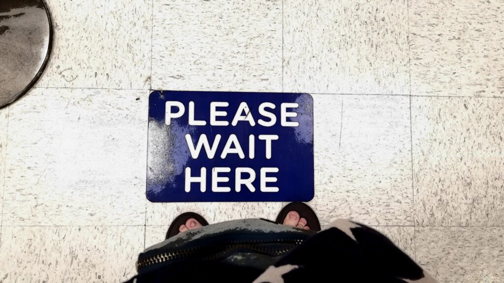 Schild am Boden auf dem steht: Please wait here