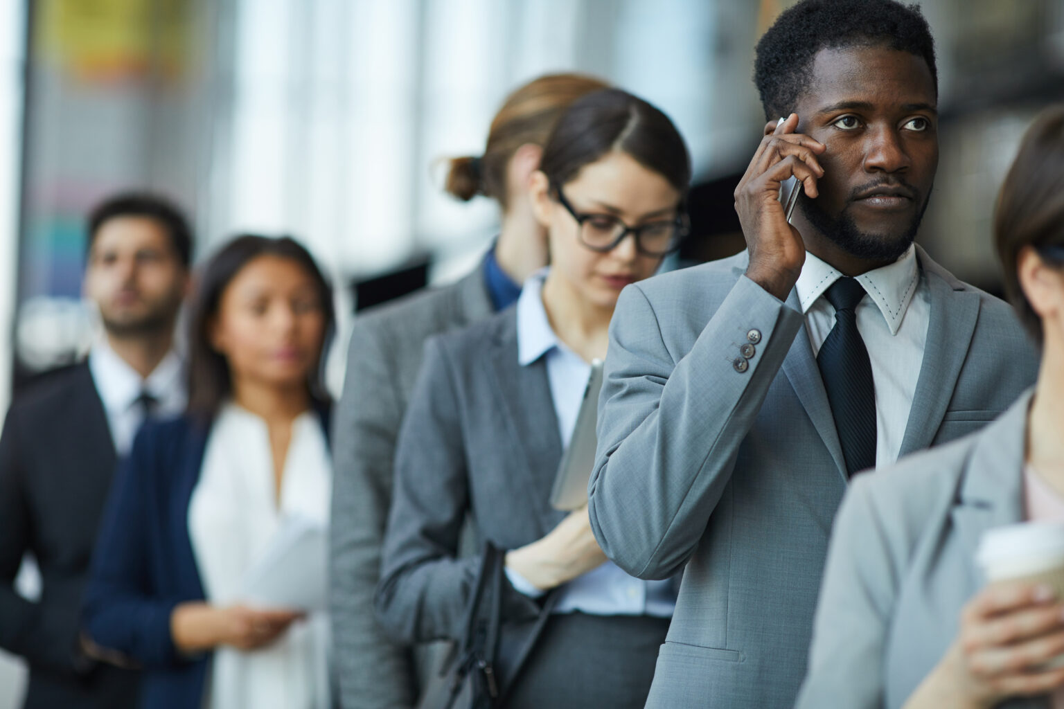 Menschen, die sich in einer Schlange anstellen und dabei auf ihre Handys blicken oder telefonieren
