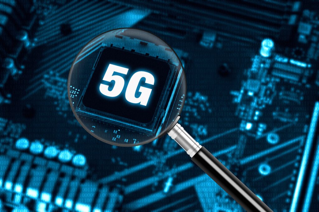 Lupe die auf Elektroteile gehalten wird. Unter der Lupe ist 5G zu sehen