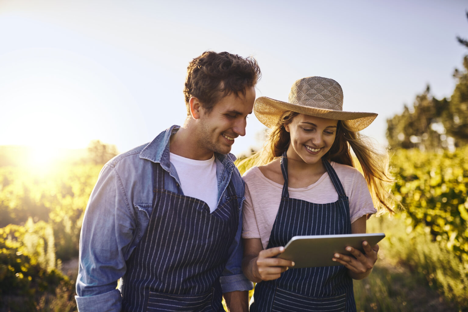 Mann und Frau stehen mit Gartenkleidung und halten ein Tablet in ihrer Hand
