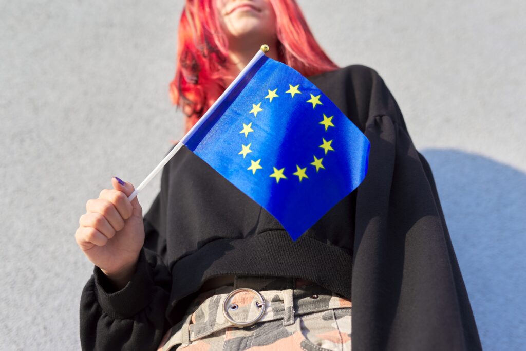 Frau mit roten Haaren bei der man das Gesicht nicht sieht hält eine EU-Fahne