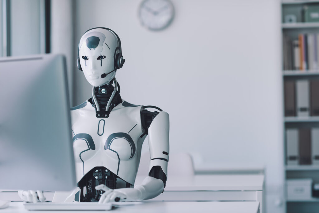 Roboter sitzt vor einem PC