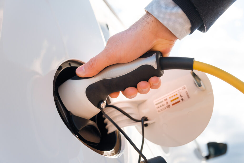 E-Auto mit einer Hand die Strom "tankt" 