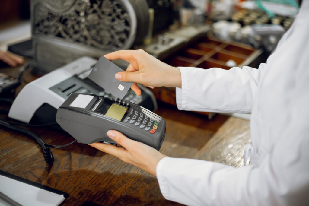 Hand zieht Bankomatkarte durch ein Zahlungsgerät