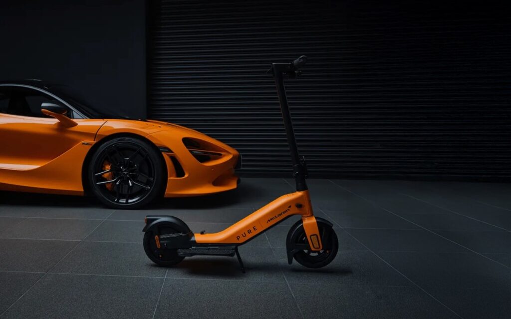 E-Scooter steht neben Sportwagen