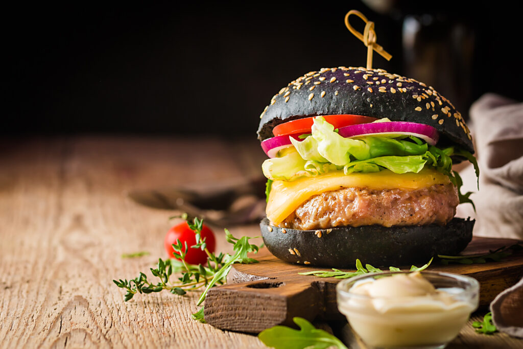 Burger mit Tomate, Zwiebel, und Käse auf einem Holzbrett
