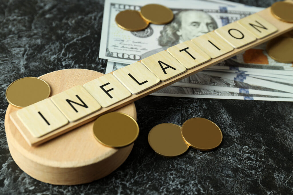 Einige Münzen ohne Zahlen und das Wort Inflation auf einem Holzbrett