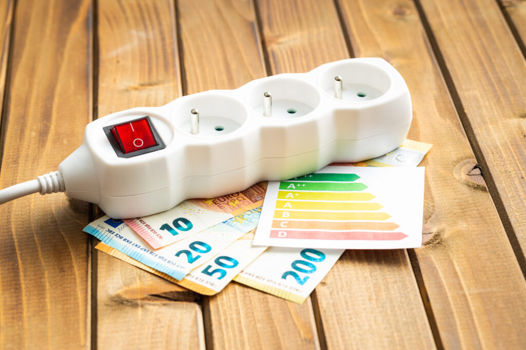 Dreifach-Steckdose mit Eurogeldscheinen dafür und eine Energietabelle