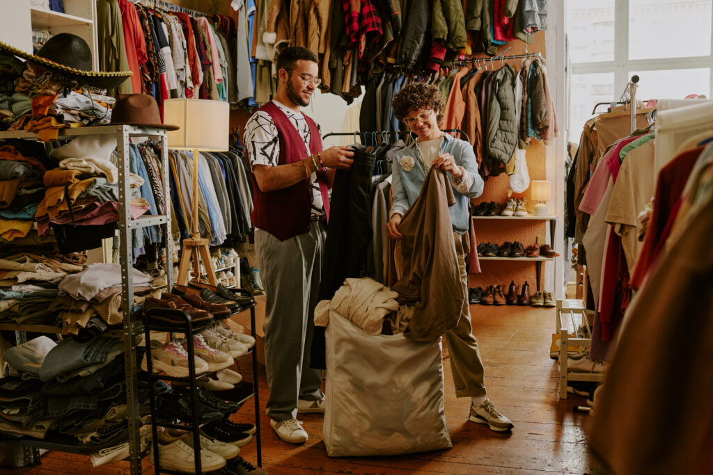 zwei Männer in einem Second-Hand-Laden halten Kleidung in der Hand