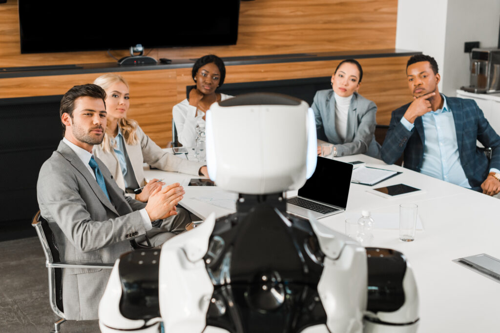 Roboter von hinten der an einem Tisch voller Menschen steht