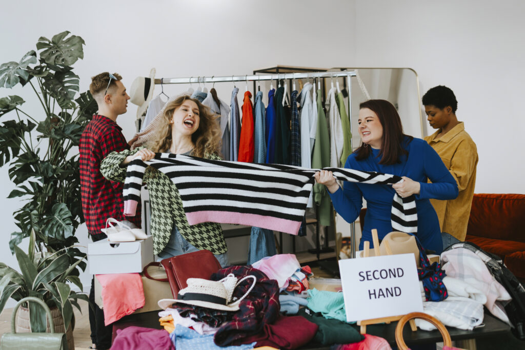 Secondhand-Bekleidung und zwei Frauen die an einem Pullover ziehen